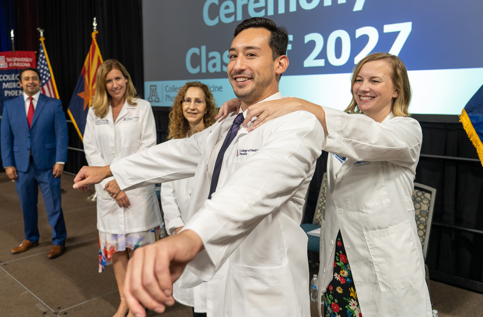 Stephanie Briney, DO, associate dean of Student Affairs, fits first-year medical student Marcus Orzabal with his white coat at the ceremony