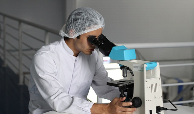 A Researcher Examines a Slide via a Microscope