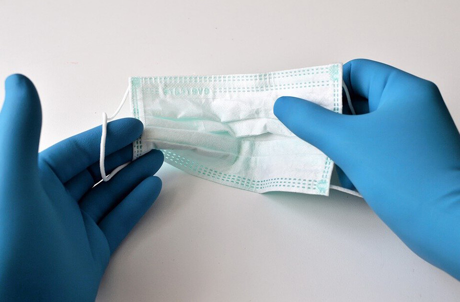 A surgical mask in gloved hands
