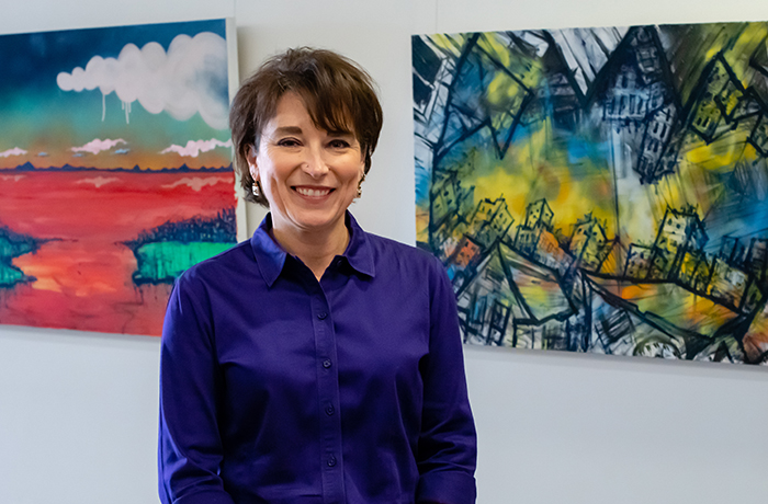 Cindi Standley, PhD, Stands in Front of Two Paintings in the HSEB