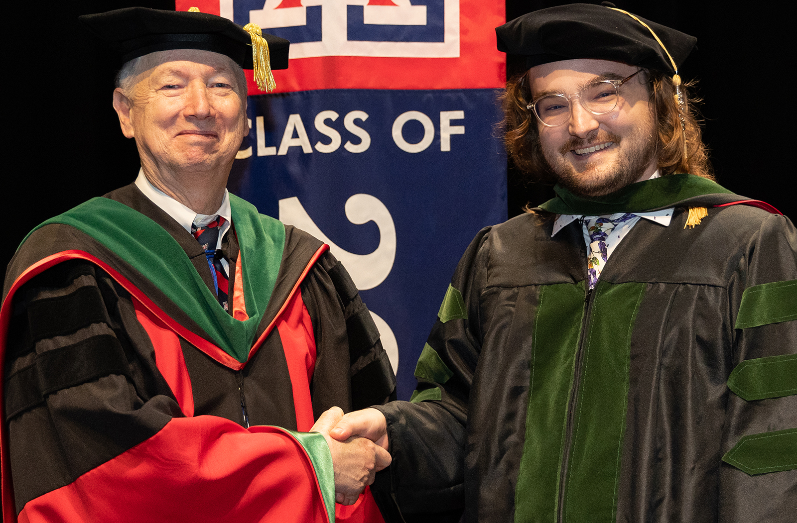 Dean Guy Reed, MD, MS, presents Austin Cotter, MD, with his diploma during the Class of 2023 Commencement