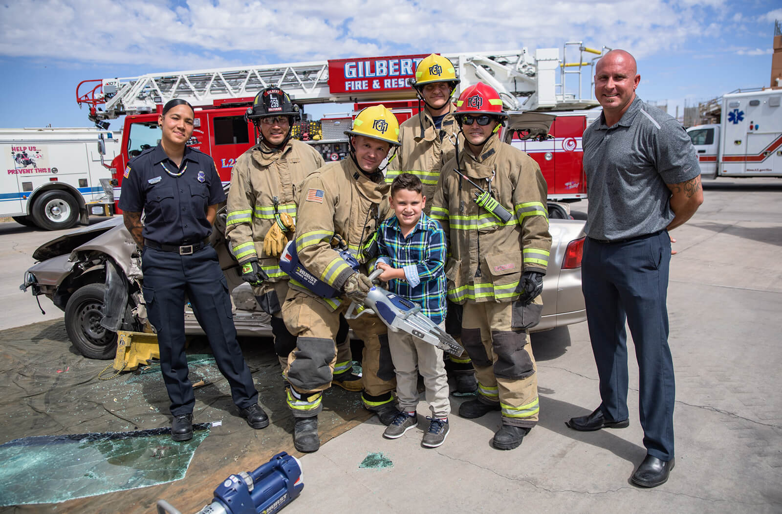 Simulated crash training crews with Glendale Fire paramedic Alex Matthews (left), her son, Jamison (holding jaws-of-life device), and Mesa and Gilbert Fire crews. Alex and Jamison were in a motor vehicle accident in December 2012, where Alex used the EPIC-TBI prehospital care guidelines to help save the life of her son.