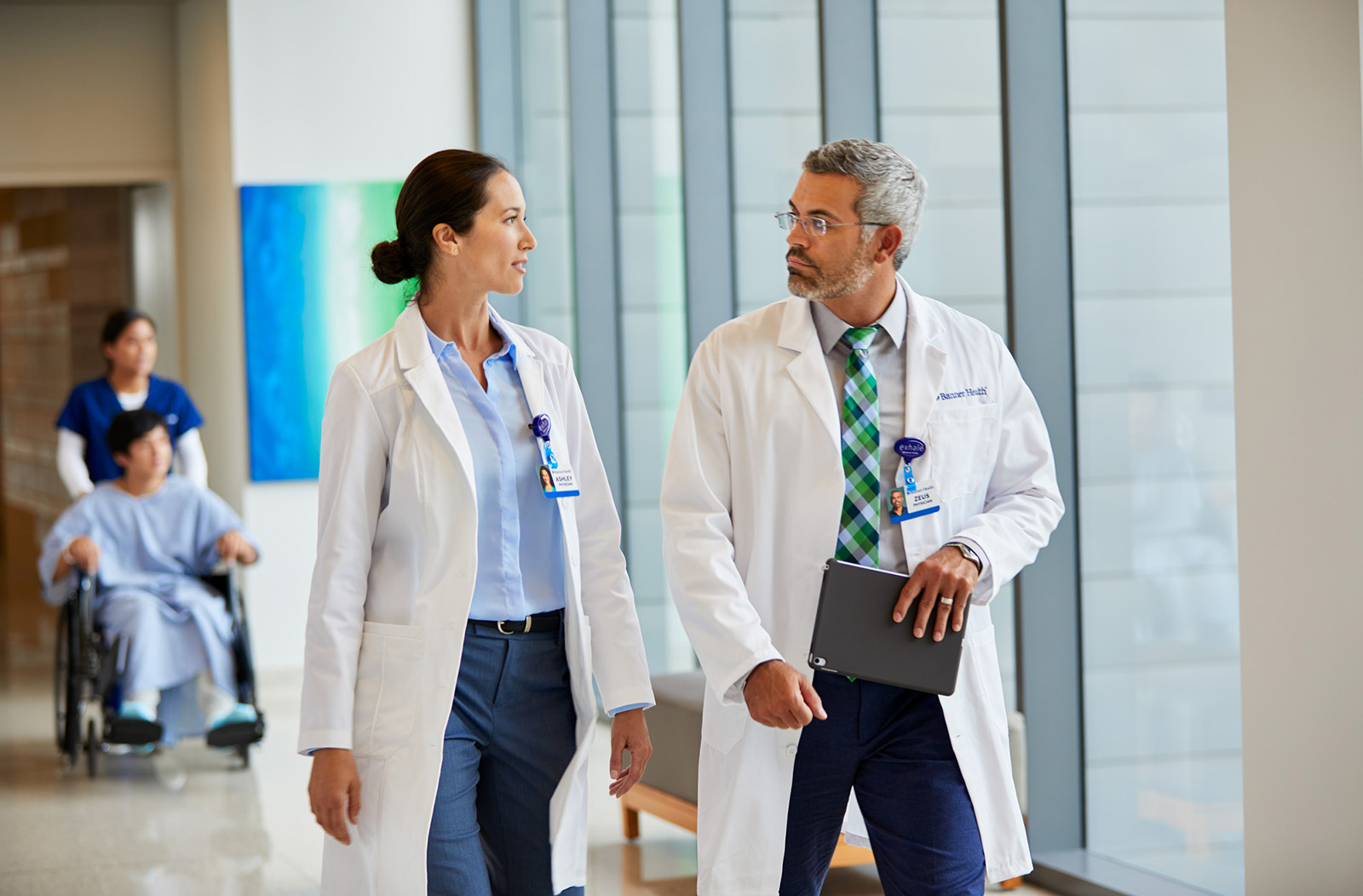 Two physicians walk down a hospital hallway