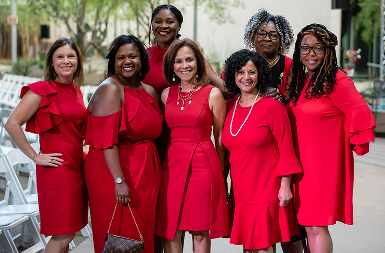 A Group of Women, Adorned in Red, Pose at the Red Dress Event