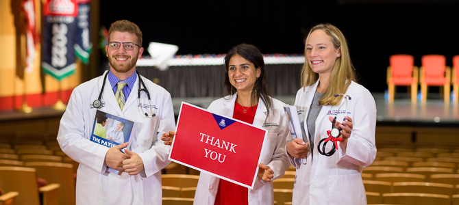 three medical students pose at white coat ceremony