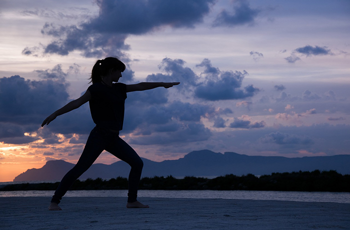 A girl performs yoga on the beach