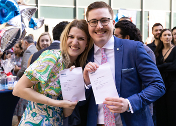 Two smiling graduates holding their diplomas