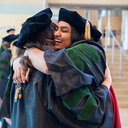 Dr. Rakkar hugs a classmate prior to the Class of 2024 Commencement