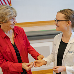 Elaine Niggemann, MD, hands Megan Vaughn her pin