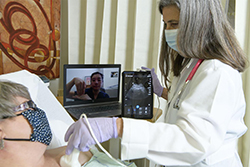 Elaine Situ-LaCase, MD, (in laptop) Receives a Livestream of the Exam Results and Assists in Diagnosing a Standardized Patient during a Telehealth Training Consultation