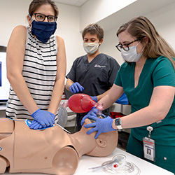 students in a group learning advanced cardiac life support on mannequins