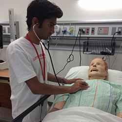 Salahudeen checking on a simulation mannequin during Summer Scrubs.