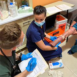 Maeliss Gelas helps treat a patient while Austin Sherwood helps document the encounter with her