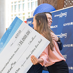 Tapia hugs Esteban Thomson after receiving her ceremonial check