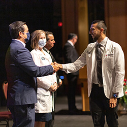 Medical student Orlando Acuna shakes hands with Francisco Lucio, JD, associate dean of Equity, Diversity and Inclusion, at the ceremony