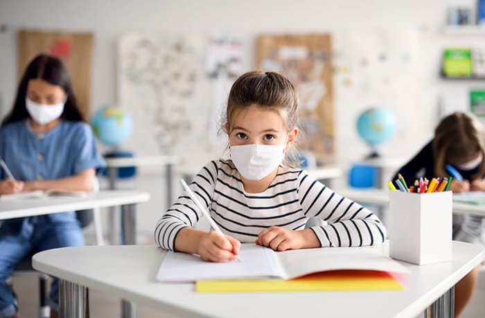 Masked Kids Sit in a Classroom Doing Schoolwork