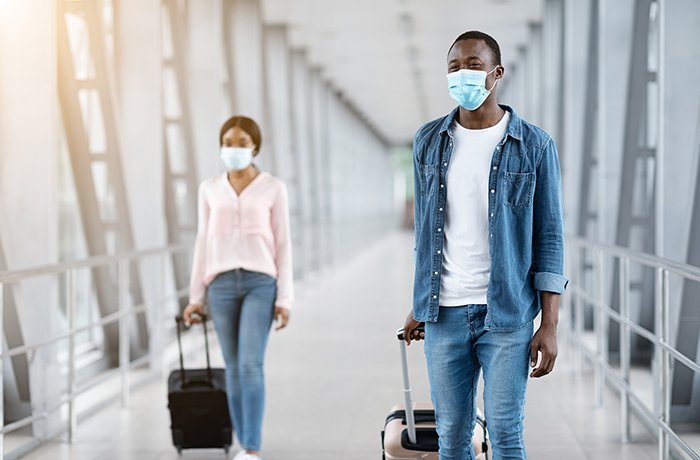 Two Travelers Walk through the Airport with Masks On