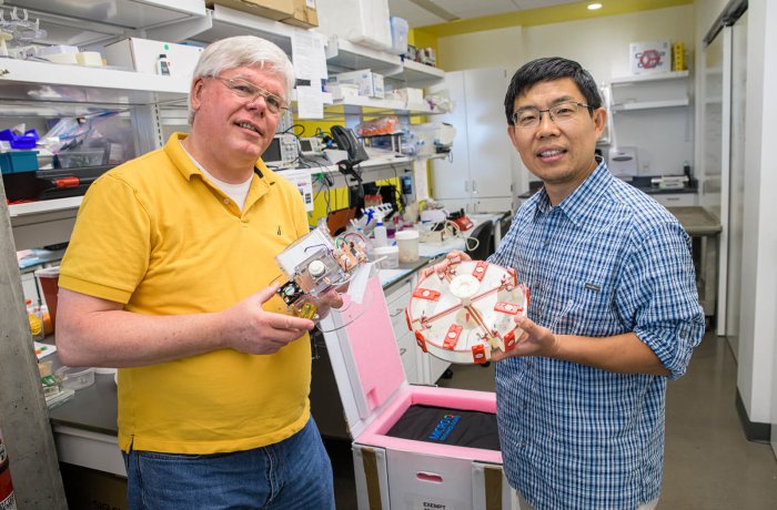 Brett Duane and Jian Gu, PhD, holding components of the Center for Applied NanoBioscience and Medicine's Smart Shipping Incubator