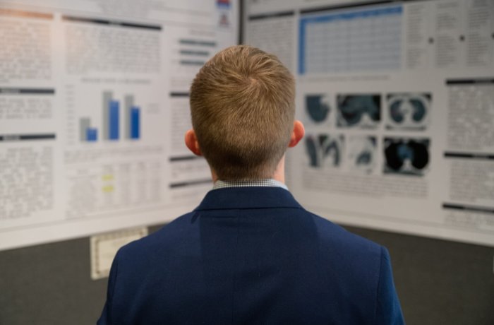 An Attendee Looks at the Research Poster of a Medical Student