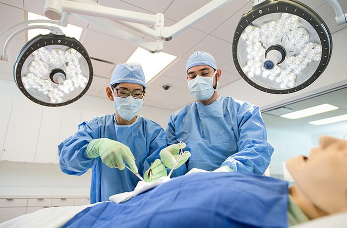 Two Medical Students Perform Surgery on a Mannequin in the Sim Center