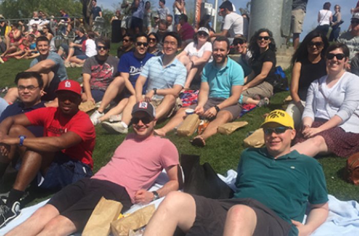 internal medicine residents lounging on the grass watching a baseball game