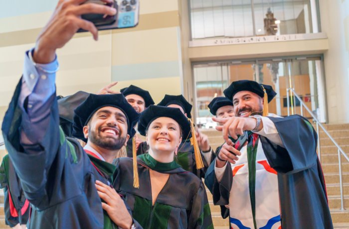 Graduates from the Class of 2024 take a selfie at Commencement