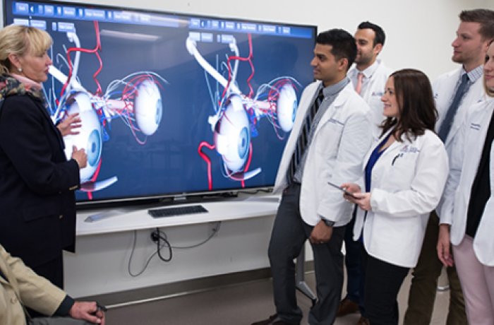 ophthalmology professors speaking to medical students in front of big monitor