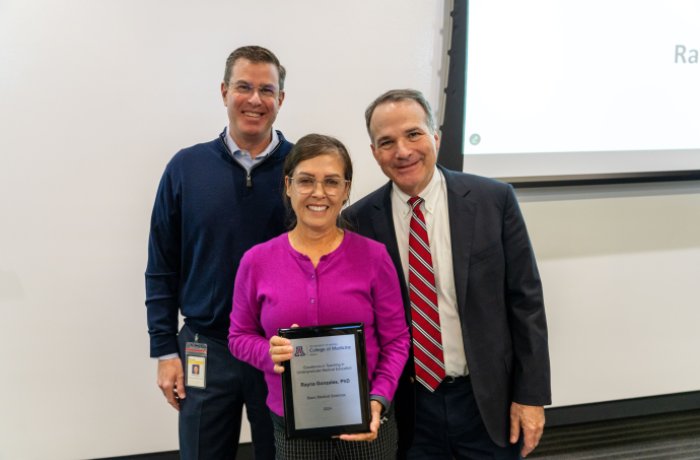 Rayna Gonzales, PhD poses with David Guttman, MD, and Dean Fredric Wondisford after receiving her award