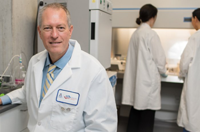 Dr. Frederic Zenhausern in His Lab with Research Happening Behind Him