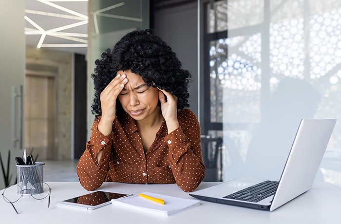 A woman suffers from a headache at her table
