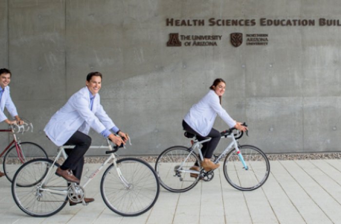 three medical students riding bicycles on the medical school campus