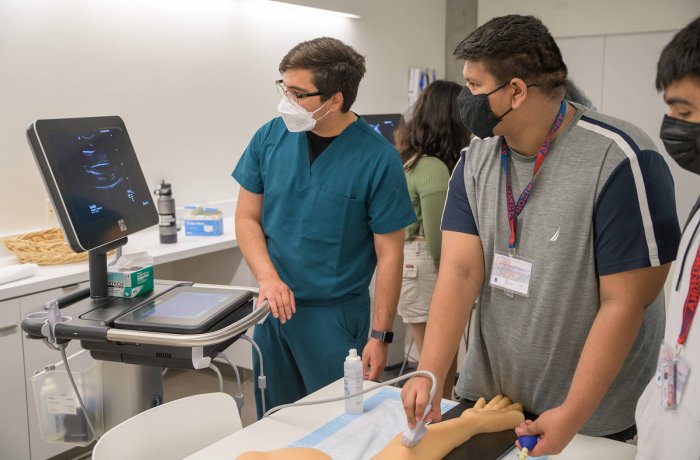 A medical student guides one of the attendees through an ultrasound