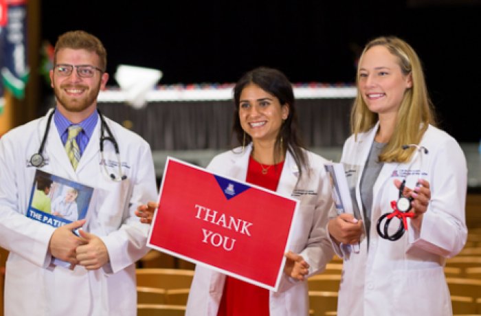 three medical students pose at white coat ceremony