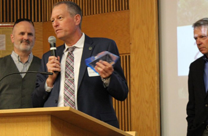 Frederic Zenhausern, PhD, MBA standing at a lectern holding a microphone