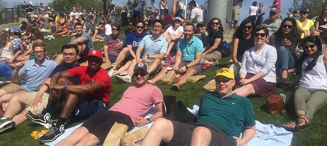 internal medicine residents lounging on the grass watching a baseball game