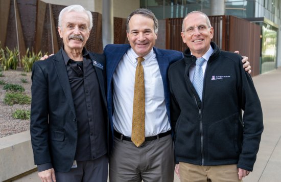 Three people posing outdoors, dressed in business attire.