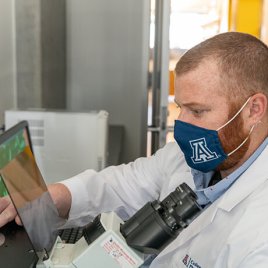 Erik Blackwood Examines a Sample through a Microscope